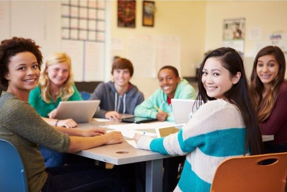 An image of students sitting around a table and working on a project
